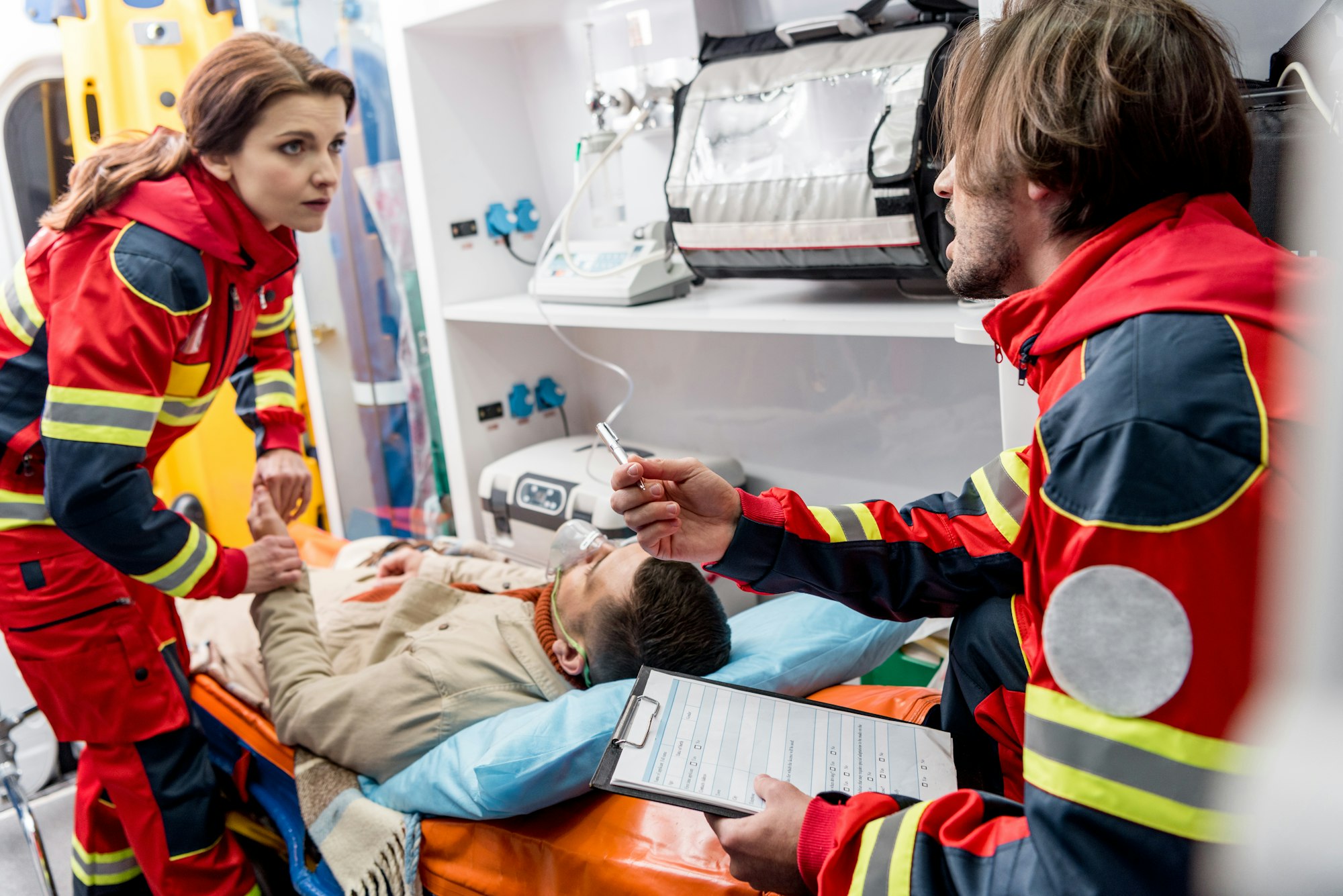 Paramedics helping unconscious man in ambulance car