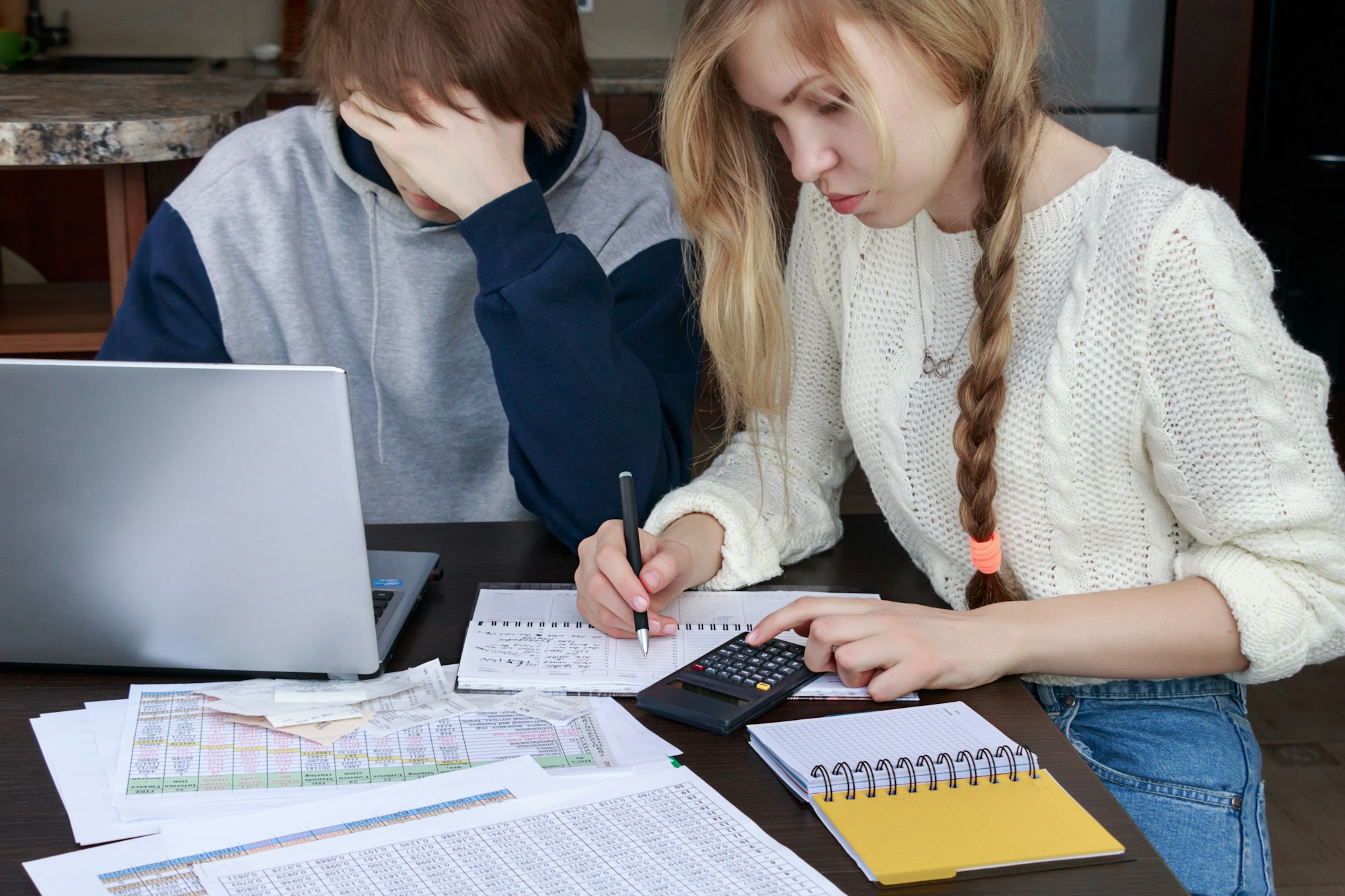 students at their desk perform calculations on a calculator and computer