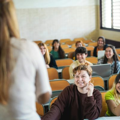 Mature teacher working with students inside classroom at school university